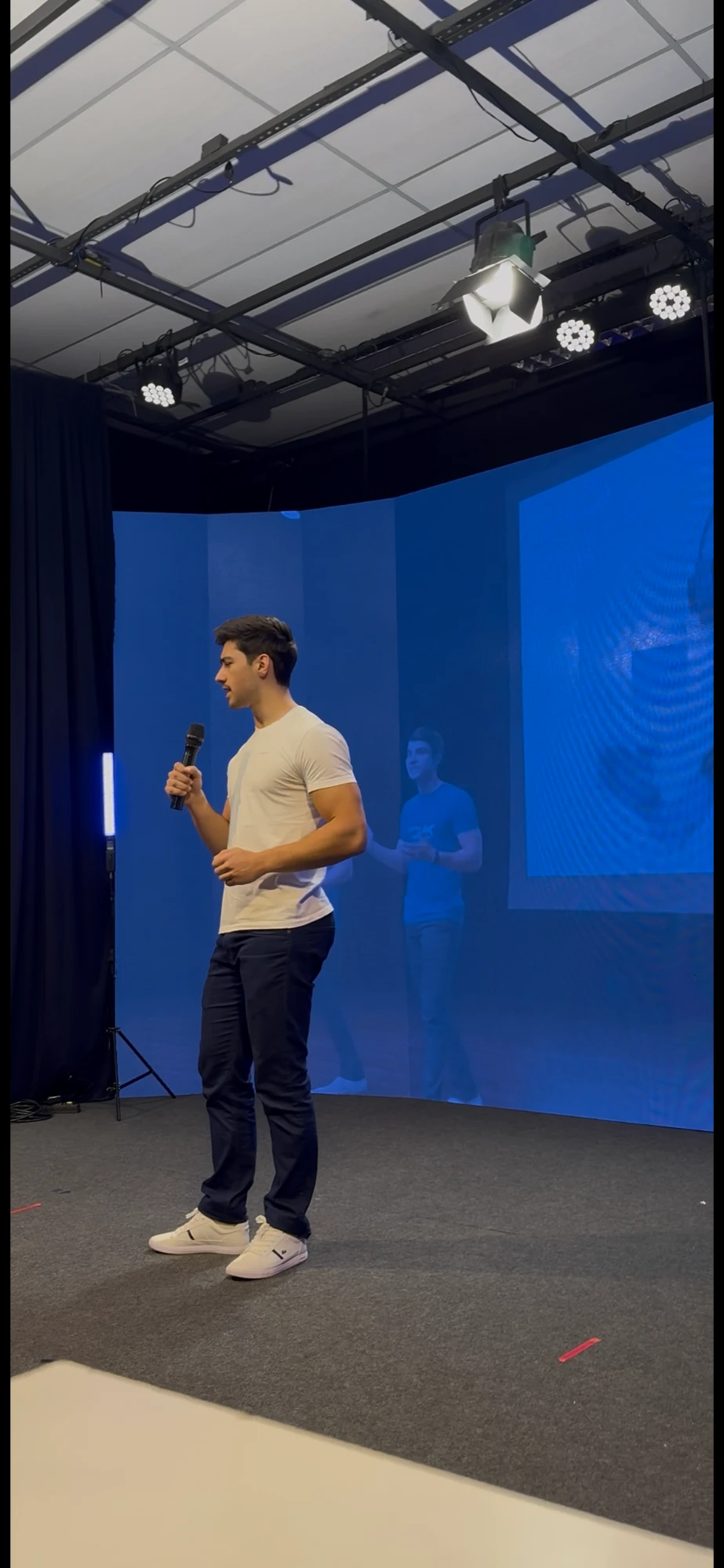 Lucas Zielke palestrando num palco com telão azul